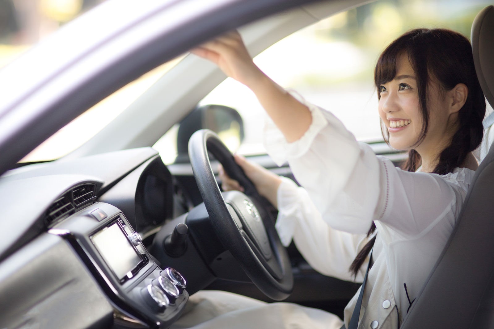 安全運転のためバックミラー調整する女子。モデル：河村友歌
