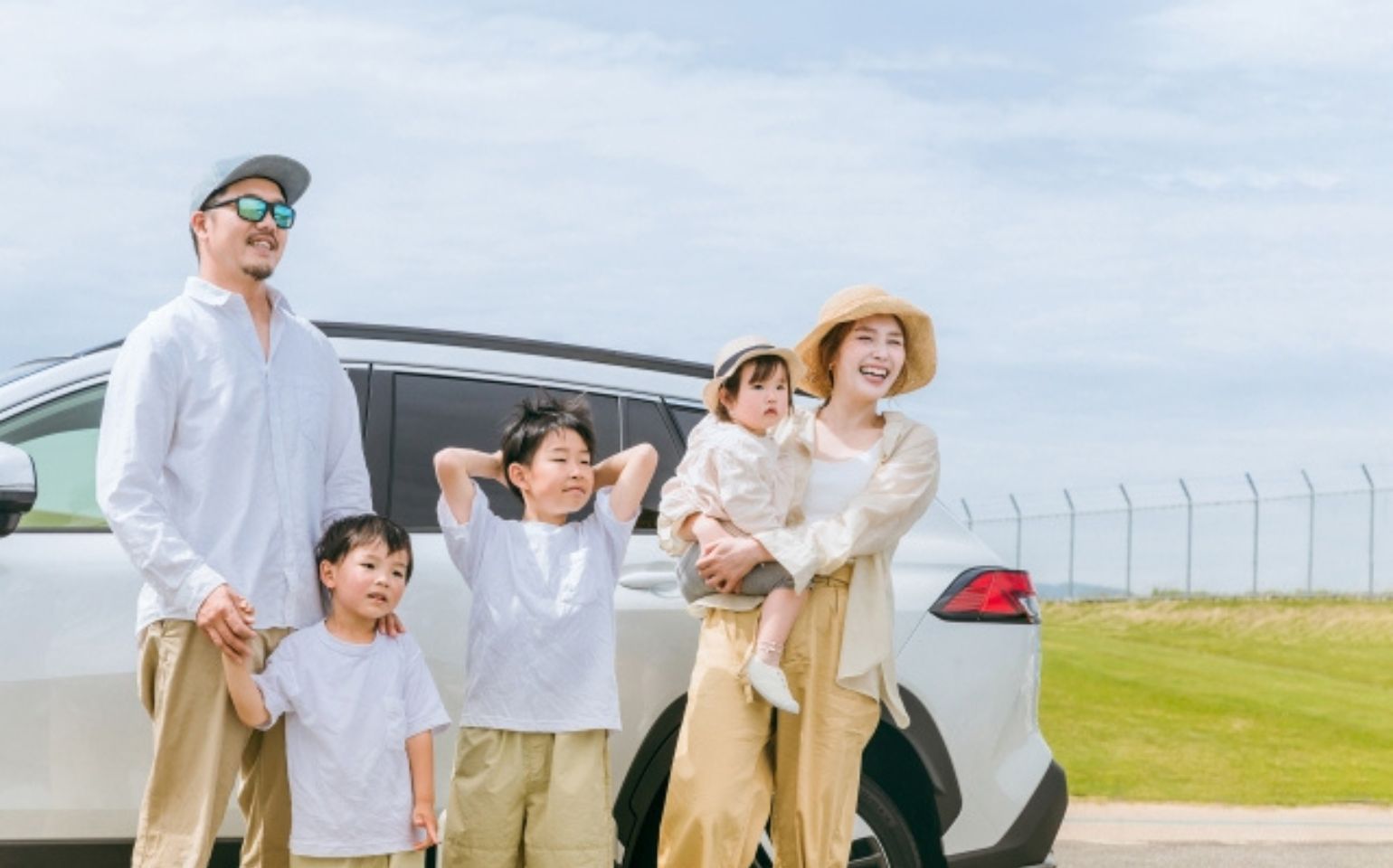 車の前で笑顔の家族